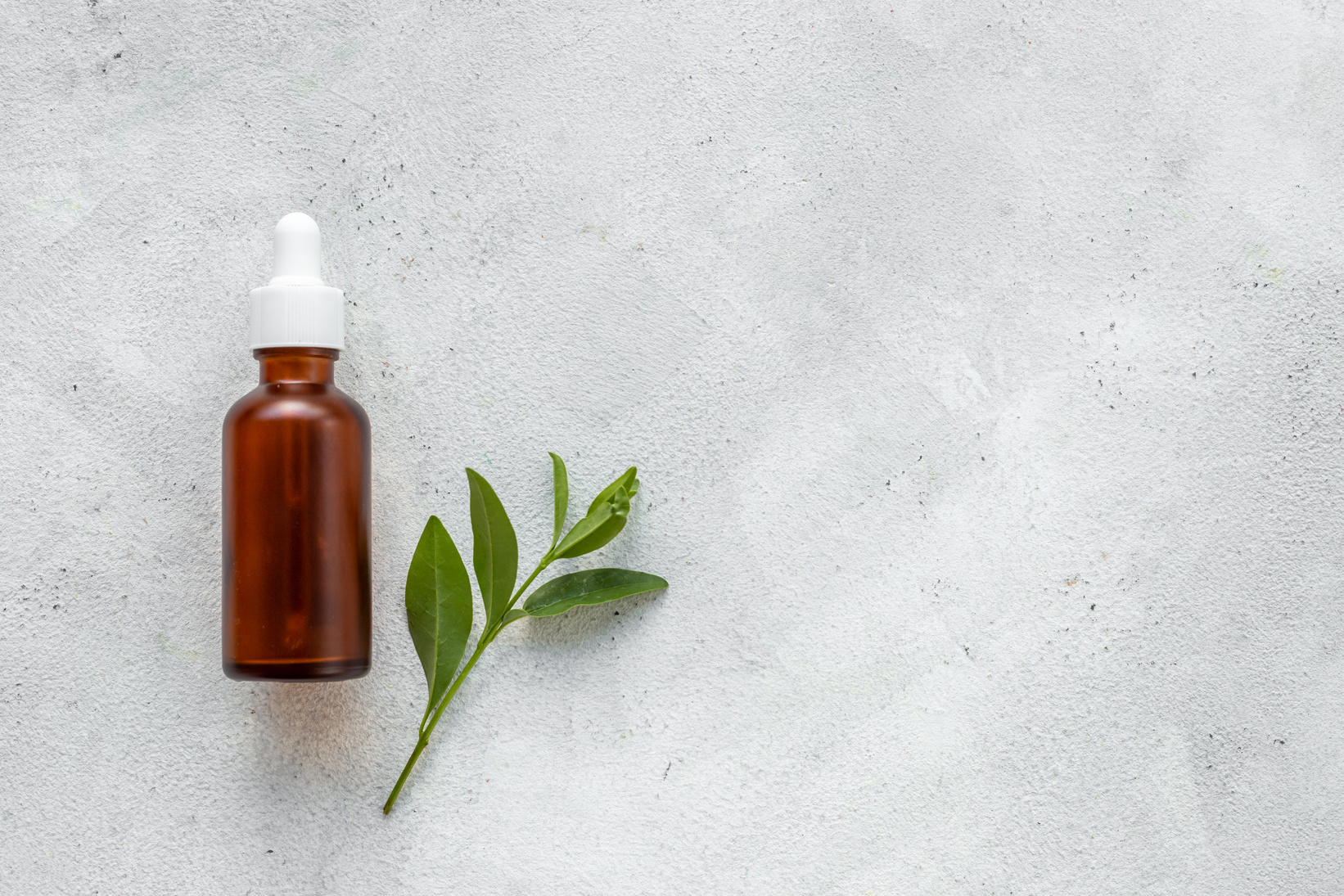 Tea tree essential oil in dropper bottle. Herbs cosmetic background